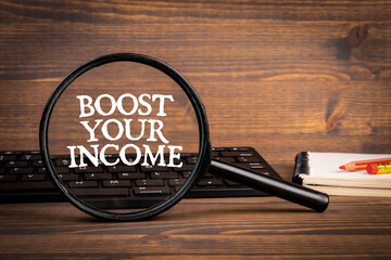 Boost Your Income. Magnifying glass and computer keyboard on the office desk