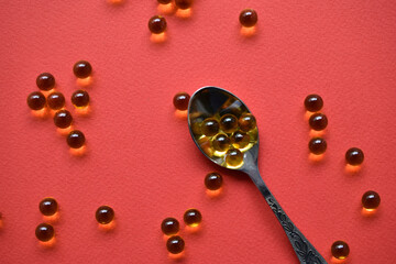 Yellow balls with fish oil on a red background. Glass yellow balls.