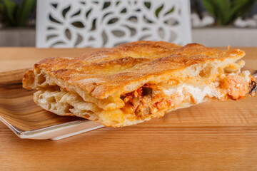 Focaccia romana ripiena di stracciata di bufala, salsiccia e melanzane fritte con pomodoro servita in una rosticceria per pranzo