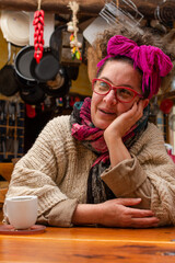 Latin woman with headscarf and glasses sitting in a kitchen paying attention