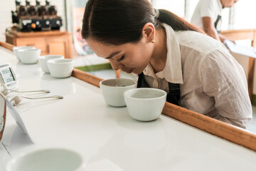 Inspector sniffing the aroma of a cup of coffee during a cupping test to measure excellence