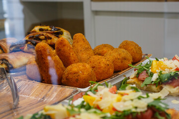 Arancini di riso in esposizione una vetrina di una rosticceria per pranzo