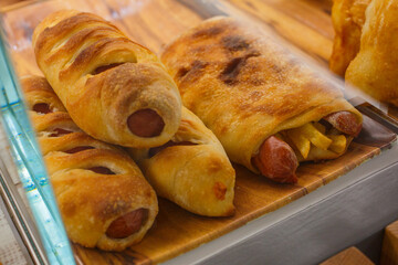 Pizze ripiene di würstel e patatine fritte in esposizione per pranzo in una vetrina di una rosticceria