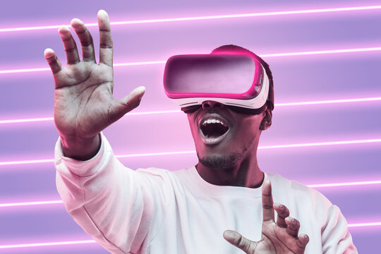 Amazed black gamer holding VR goggles to experience wonderful metaverse virtual space