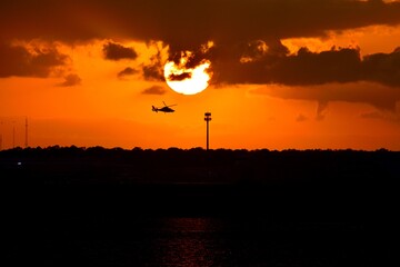 Vibrant orange sky with helicopter silhouette background.