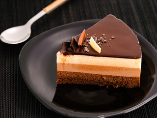 A piece of chocolate mousse cake on a black plate.
