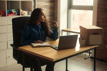 Side view. Young business woman is sitting at the table and. On the table is a laptop, smartphone and. On the computer screen graphs and charts. The student is studying online. Blogger. entrepreneur