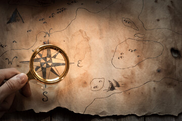 a man looks at an old map through a magnifying glass, the concept of travel and treasure hunting