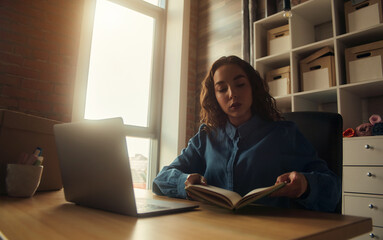 Side view. Young business woman is sitting at the table and. On the table is a laptop, smartphone and. On the computer screen graphs and charts. The student is studying online. Blogger. entrepreneur