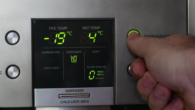 Man adjusting the temperature of his fridge on a Digital Panel of a refrigerator. Temperature displayed in degree celsius, Energy and electricity costs.