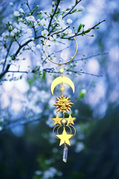 Solar golden amulet on blossoming branch, natural abstract spring natural background. Sun symbol of spring equinox. pagan witch ritual, spiritual wiccan practice.