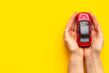 Toy car in hands, top view. Car insurance or driving safety concept
