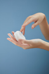 Front view of hand model holding cotton pad in blue background for cosmetic advertising	
