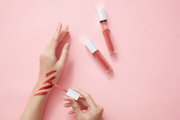 Top view of hand model using lipstick on hand in pink background for cosmetic advertising	