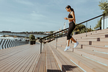 Young woman in sportswear exercising on a river promenade
