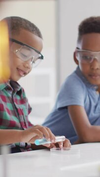 Video of happy african american boys wearing glasses during chemistry lesson