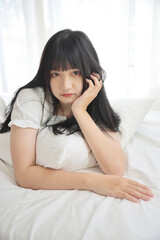 Beautiful young Asian woman sleeping on bed relaxing in the morning light with white room