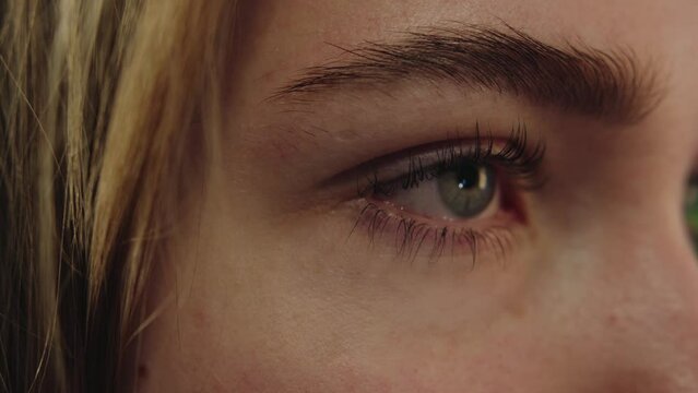 Young caucasian girl with bushy eyebrows opens her blue eyes after eyelash lamination in a beauty salon. Close-up