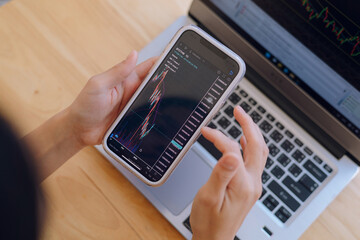 Woman is checking Bitcoin price chart on digital exchange on smartphone, cryptocurrency future price action prediction.