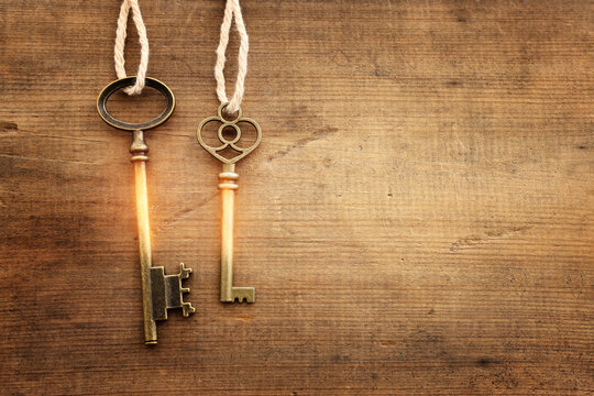 Top view image of old keys with golden light over wooden background