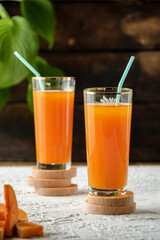 pumpkin juice with orange, orange juice in a glass with a straw, vegetable fresh in a transparent glass, two glasses with juice on a concrete table, sun rays, creative photo of a drink for a magazine,