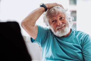 Cheerful elderly man watching video stretching neck