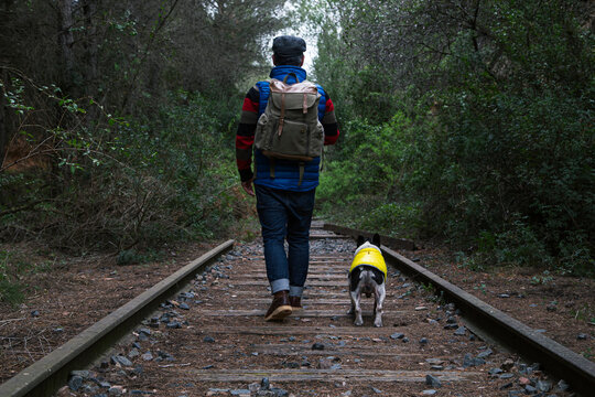 Male traveler with dog walking on rails