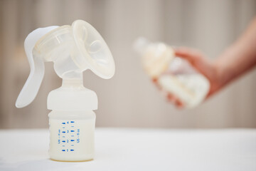 manual breast pump on background of hand with bottle with milk