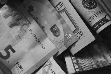 Cash banknotes dollars and euros are mixed up, a close-up shot. Black and white image.