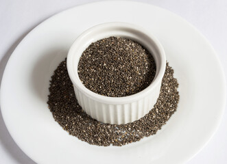 Small white bowl with chia seeds on a small plate
