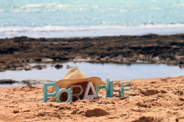 Minimalist portrait of a paradise beach with a paradise sign and a straw hat, minimalist summer background, beach and summer. 