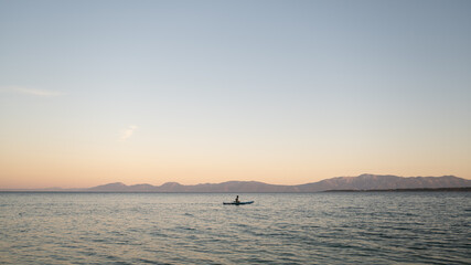 Child on sup board at sunset