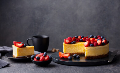 Cheesecake dessert with fresh berries and cup of coffee. Grey background. Copy space. - obrazy, fototapety, plakaty