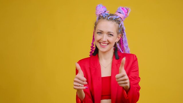 Showing thumbs up personally to someone, sign of compliment and praise, expressing approval and admiration. Woman with afro braids dreads colorful hair. Pointing to camera. Delighting emotions