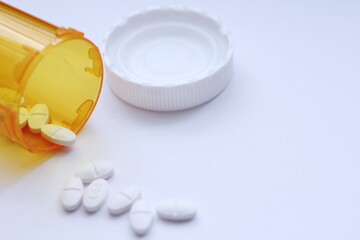 Oval pills and orange pill bottles were spread out on the white tabletop.