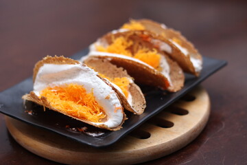 Thai Food, Thai Crispy Pancakes served in a black plate on a brown wooden table.