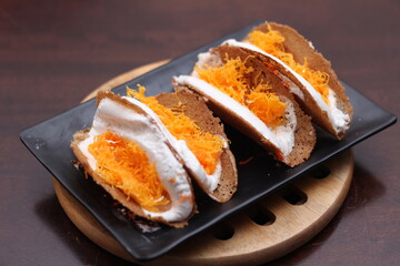 Thai Food, Thai Crispy Pancakes served in a black plate on a brown wooden table.