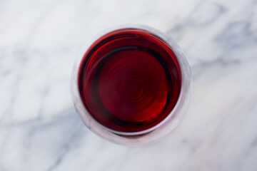 Red wine in glass. Marble background. Close up. Top view.