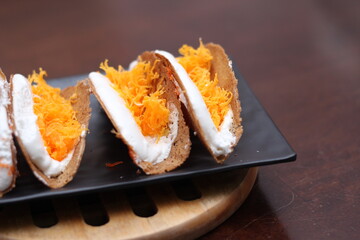 Thai Food, Thai Crispy Pancakes served in a black plate on a brown wooden table.