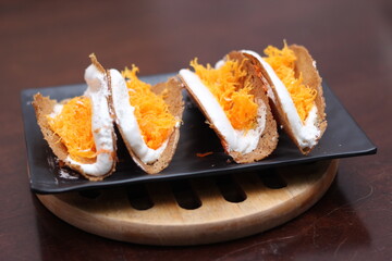 Thai Food, Thai Crispy Pancakes served in a black plate on a brown wooden table.