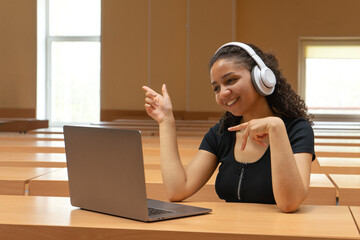 Smiling african woman with headset studying online, using laptop