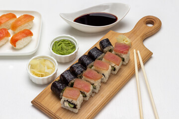 Nori maki, sushi with salmon and tuna on cutting board.