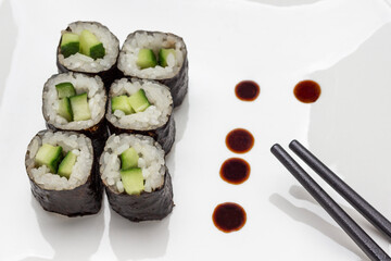 Nori maki and black chopsticks. White background.
