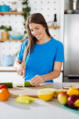 Young woman preparing salad in the kitchen