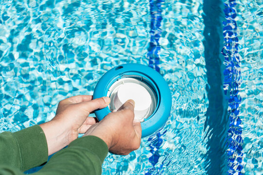 Pool chlorine tablets to balance the pH of the water for cleaning and maintenance. Introduction of a tablet in a chlorine float in an outdoor pool