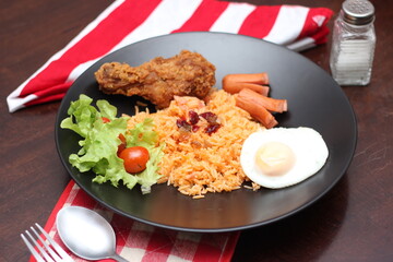 American fried rice served with sausages, cucumbers, shredded vegetables in a gray plate on a white table with seasoning.