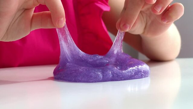 Play with texture slime, stretching the sticky substance. Child's hand of a child holds touches purple slime, squeezing it. Press your fingers on a liquid toy. 4K.