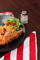 American fried rice served with sausages, cucumbers, shredded vegetables in a gray plate on a white table with seasoning.