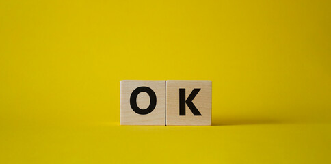 Ok symbol. Concept word Ok on wooden cubes. Beautiful yellow background. Business and Ok concept. Copy space.