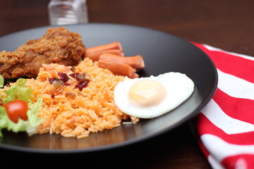 American fried rice served with sausages, cucumbers, shredded vegetables in a gray plate on a white table with seasoning.